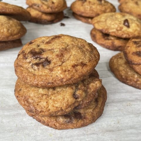 browned butter chocolate chip cookies stacked on parchment