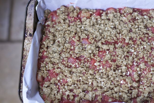 layering the strawberry rhubarb bars in a baking pan