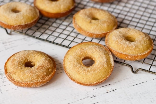 baked cider doughnuts cooling rack, dipped in cinnamon and sugar