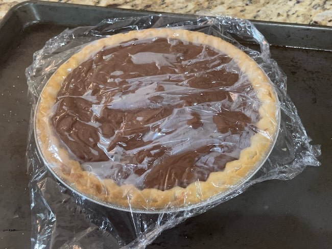 chocolate cream pie with saran wrap ontop to prevent forming a skin